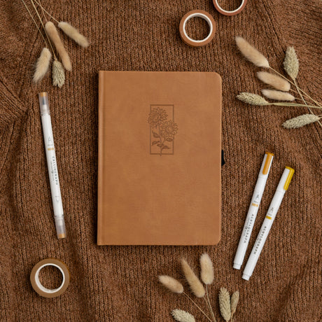 Let your ideas bloom with this warm and inviting Sunflower Notebook. Wrapped in a rich caramel vegan leather cover, it features a beautifully debossed pair of sunflowers—symbols of joy, hope, and creative energy. Whether you're journaling your thoughts or planning your next big project, this notebook brings a little sunshine to every page.

✨&nbsp;Features You’ll Love

Elegant debossed sunflower illustration&nbsp;for a clean, understated botanical look

Caramel vegan leather cover&nbsp;that’s soft to the to