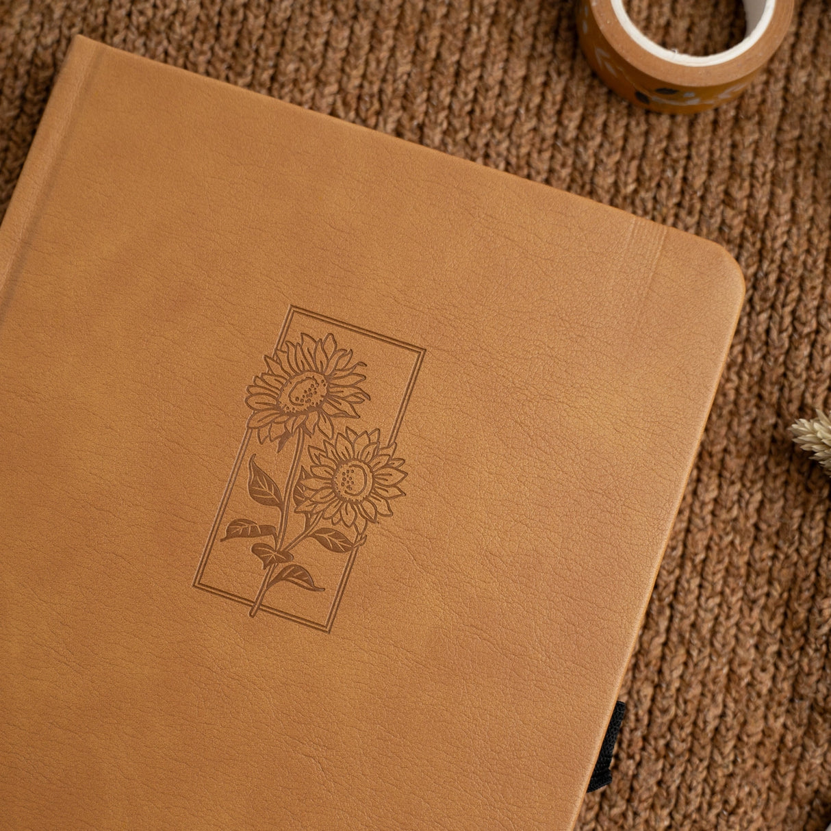 Let your ideas bloom with this warm and inviting Sunflower Notebook. Wrapped in a rich caramel vegan leather cover, it features a beautifully debossed pair of sunflowers—symbols of joy, hope, and creative energy. Whether you're journaling your thoughts or planning your next big project, this notebook brings a little sunshine to every page.

✨&nbsp;Features You’ll Love

Elegant debossed sunflower illustration&nbsp;for a clean, understated botanical look

Caramel vegan leather cover&nbsp;that’s soft to the to