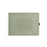 Introducing the&nbsp;Lovely Lilies Heirloom&nbsp;notebook.&nbsp;This&nbsp;Letter Sized&nbsp;notebook features&nbsp;a full-cover&nbsp;floral border design, stamped in&nbsp;white&nbsp;on a&nbsp;sage green buckram&nbsp;cover. The design spans the entire notebook, with special details on the back cover, spine, and front cover.



Designed with&nbsp;lined pages, this journal provides a structured space for thoughtful reflections, personal writing, note-taking, or planning. Whether you're using it as a memory-kee