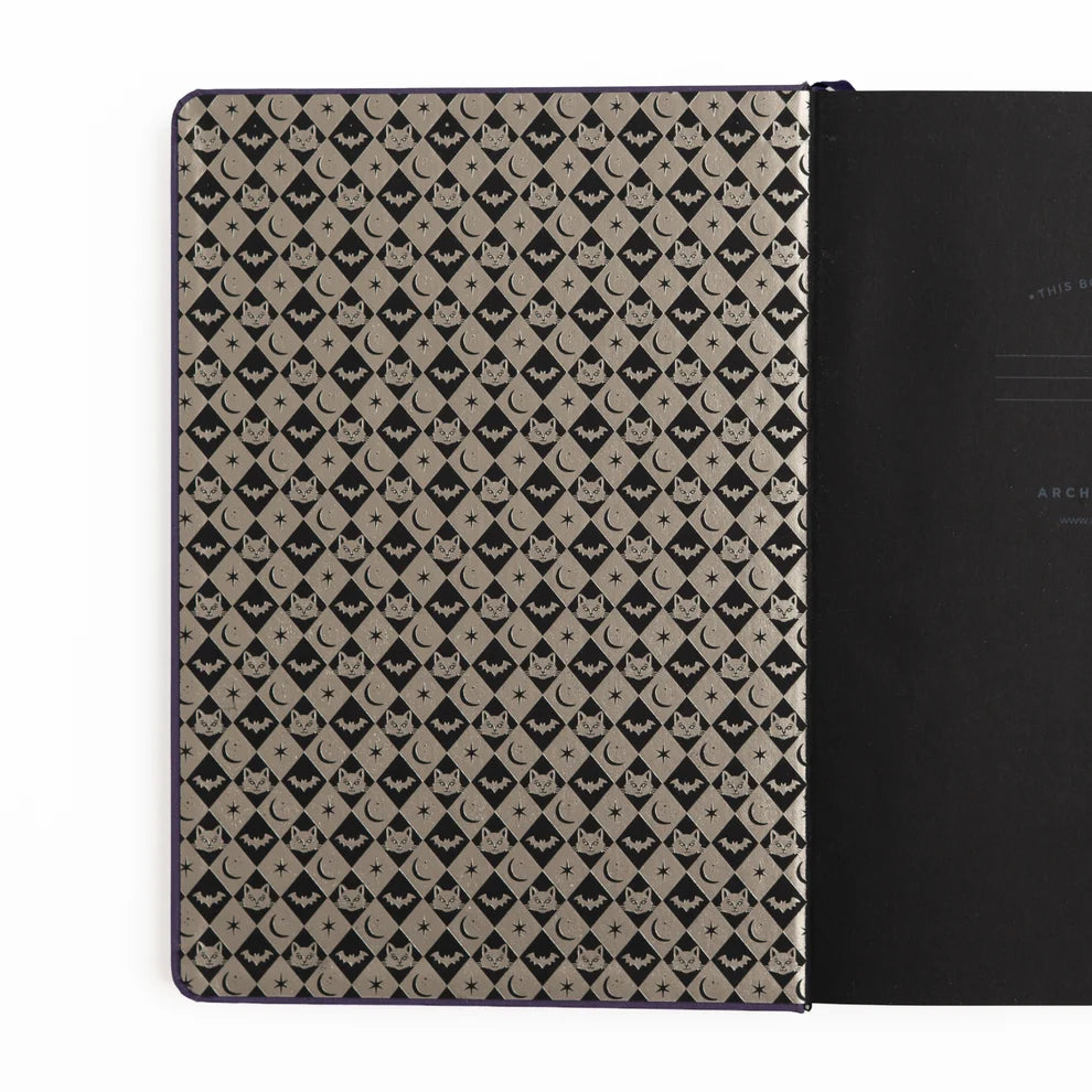 The Bewitched Notebook captures the playful spirit of Halloween with a charming black cat perched atop a broomstick beneath a crescent moon, surrounded by twinkling stars and fluttering bats.