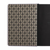 The Bewitched Notebook captures the playful spirit of Halloween with a charming black cat perched atop a broomstick beneath a crescent moon, surrounded by twinkling stars and fluttering bats.