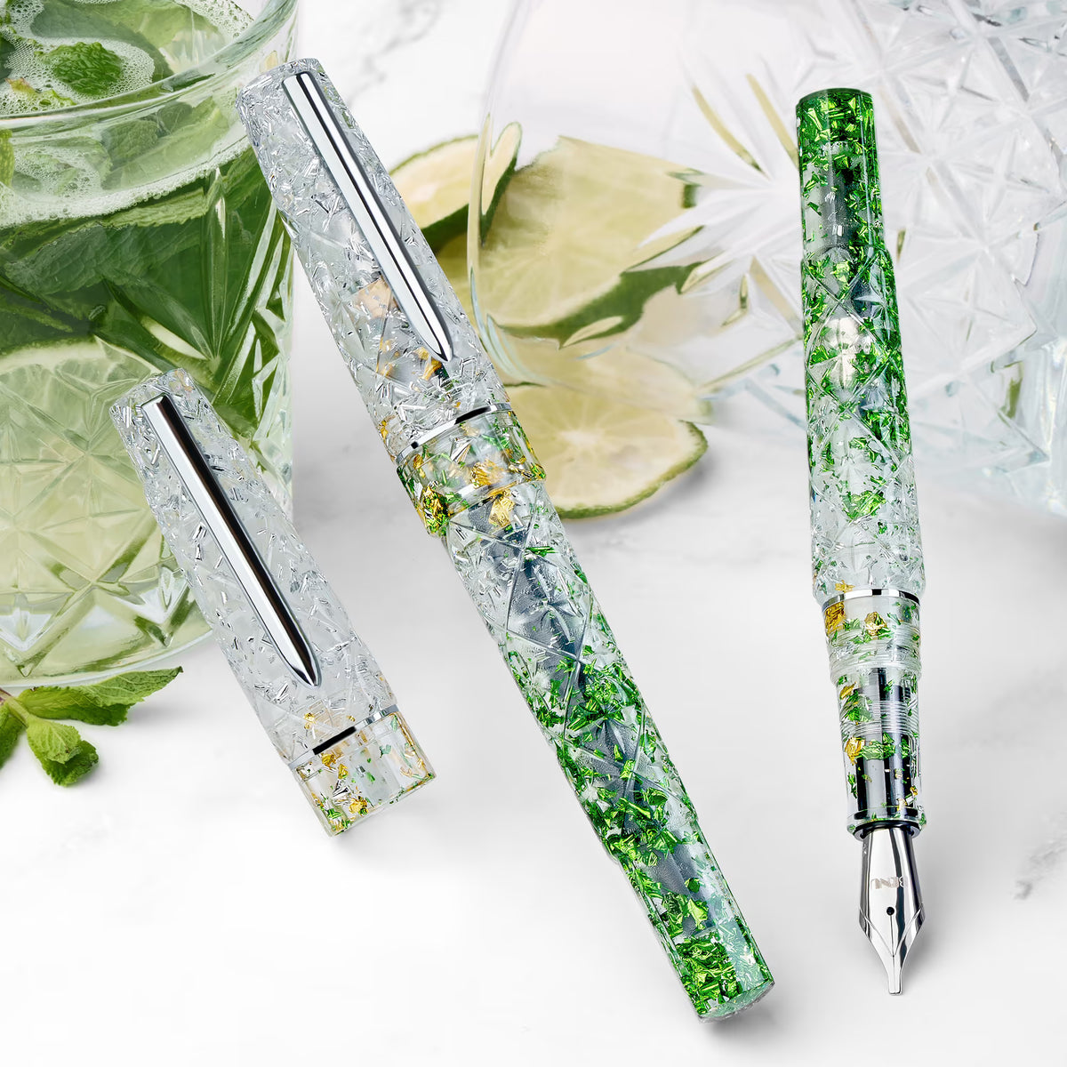 BENU Cocktail Hour Fountain Pen - Mojito

Inspired by the classic Mojito cocktail, this pen combines a transparent acrylic body with silver, green, and golden sparkling particles in a lively faceted design that beautifully interacts with light. The diamond-cut inspired surface creates depth, reflections, and movement across the material, giving the pen a fresh, glass-like appearance reminiscent of ice, lime, and sparkling summer cocktails. Bright, energetic, and refreshing, Mojito brings a playful yet sophi