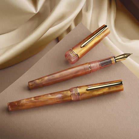 BENU presents the newest Haute Collection — a line of elegant, fashion-inspired pens that blend classic charm with bold, modern flair. The designs include both subtle and vibrant styles, showcasing BENU’s signature glitter and color artistry. Each pen features a faceted body with alternating wide and slender facets, complemented by either gold-plated or chrome-plated trims for a sleek, timeless look.

Lustre pen glows with warm swirls of amber and blush, finished in radiant gold trim.Quietly luxurious, Lust