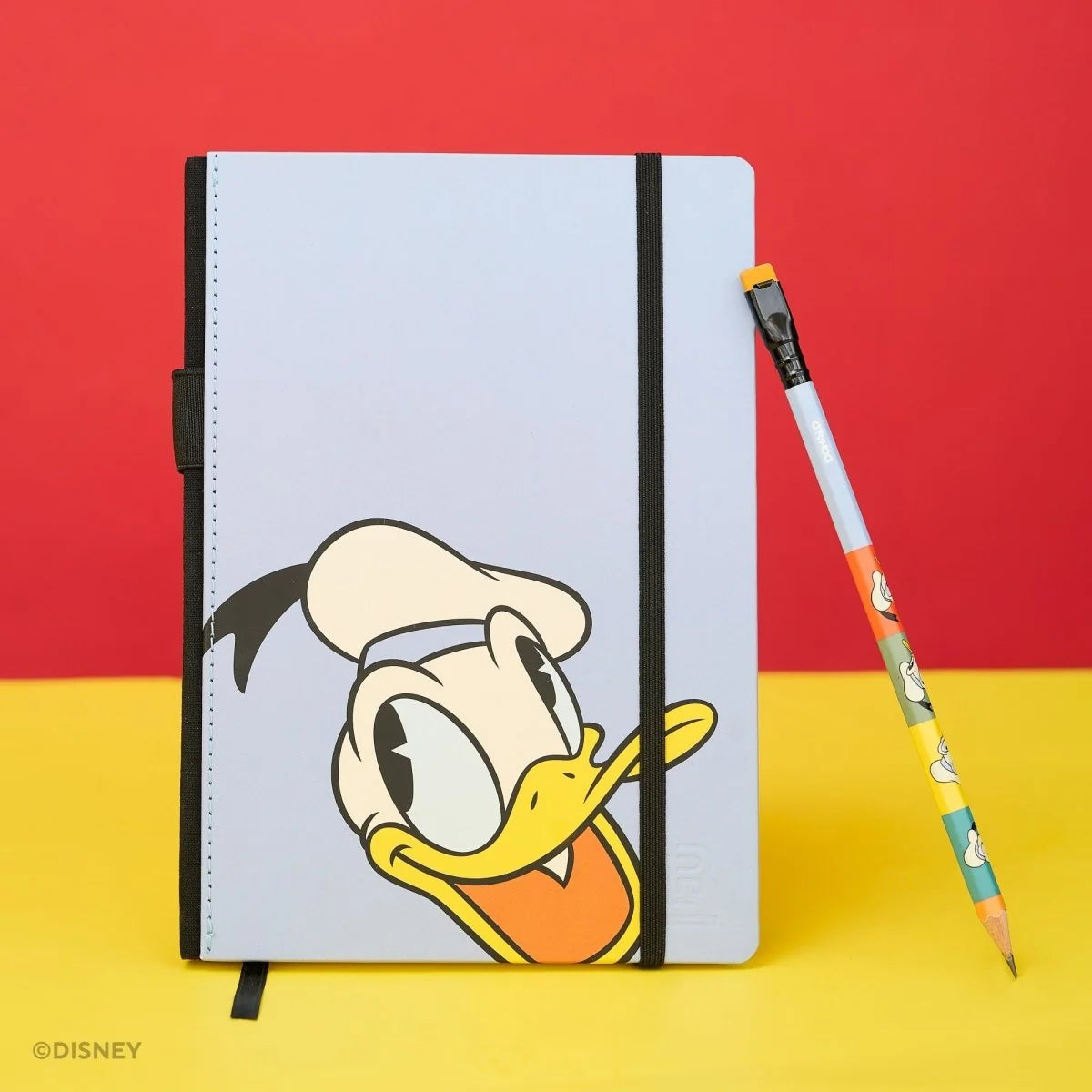 This medium notebook includes 160 pages of 100GSM blank paper and a matte hardcover featuring Donald Duck and Daisy Duck. It also has a built-in pencil holster that comes loaded with a Donald Duck Blackwing pencil.