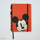 This medium notebook includes 160 pages of 100GSM blank paper and a matte hardcover featuring Mickey and Minnie Mouse. It also has a built-in pencil holster that comes loaded with a Mickey Mouse Blackwing pencil.