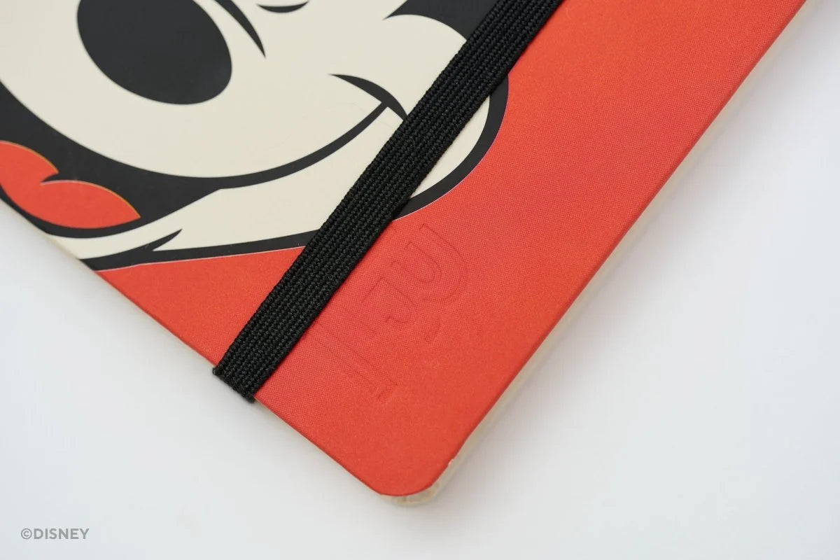 This medium notebook includes 160 pages of 100GSM blank paper and a matte hardcover featuring Mickey and Minnie Mouse. It also has a built-in pencil holster that comes loaded with a Mickey Mouse Blackwing pencil.