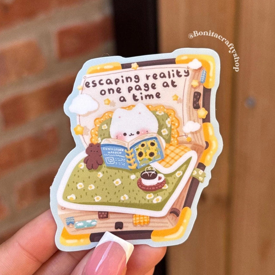 Escape into a cozy world with this matte vinyl sticker featuring a cute kawaii cat curled up with a book and the dreamy quote “Escaping reality one page at a time.” This aesthetic sticker is perfect for book lovers, readers, and anyone who loves cozy, comforting designs.

♡ STICKER DETAILS ♡
~ Sticker size: 2.5’’ inches
~ Printed on matte sticker paper
~ Matte Laminate finish ✨
~ ONLY Handwash. This sticker is not dishwasher or microwave safe.