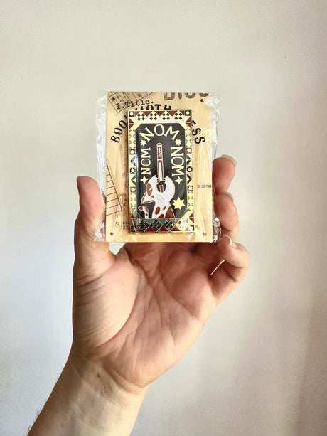 This design is part of my Book Worm Idiom Series. Book Swallower is found in Swedish and Welsh (Or so my research told me) and this design is so intricate! It has dark academia / cottage core vibes and is an adorable cat swallowing a book!&nbsp;

2.65 inches tall, gold metal lapel pin with "hard" enamel colors. Black rubber clasps. Packaged in a small plastic bag with a card backing.