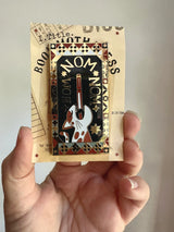 This design is part of my Book Worm Idiom Series. Book Swallower is found in Swedish and Welsh (Or so my research told me) and this design is so intricate! It has dark academia / cottage core vibes and is an adorable cat swallowing a book!&nbsp;

2.65 inches tall, gold metal lapel pin with "hard" enamel colors. Black rubber clasps. Packaged in a small plastic bag with a card backing.