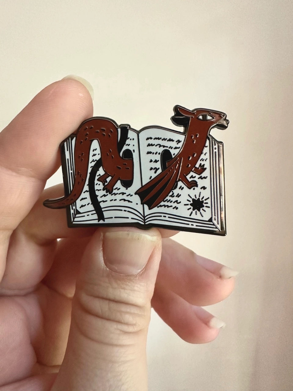 These pins are a lovely, small and cute piece to show off on your clothes, book bags, or wherever you show off your pins!

1.75 inches across, black metal lapel pin with "hard" enamel colors. Black rubber clasps. Packaged in a small plastic bag with a card backing.

"Are your customers book hoarders? No one loves a good horde like a dragon. And I love a good pun, so I combined the two into this Book Wyrm design! Wyrm is the old English word for dragon."