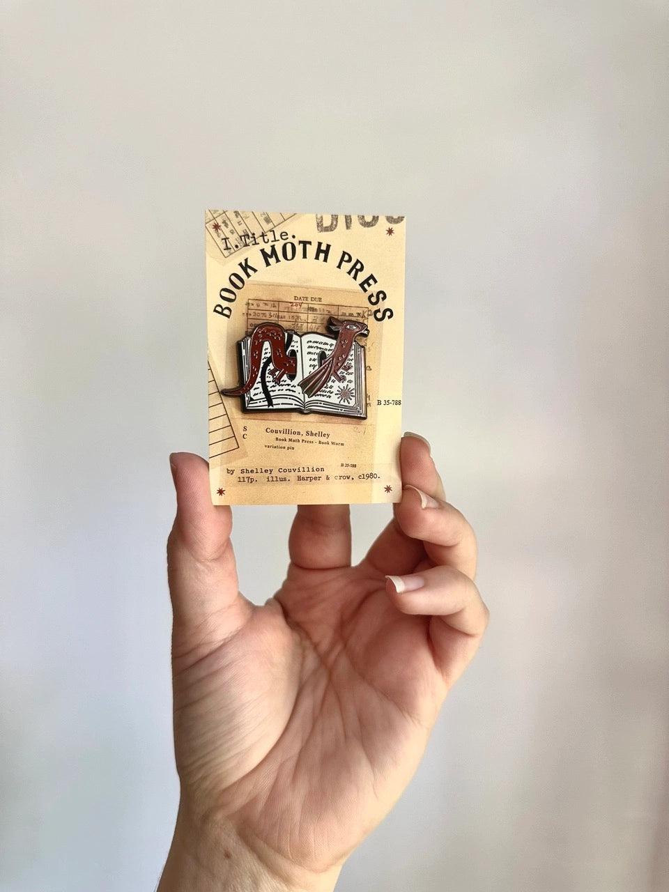 These pins are a lovely, small and cute piece to show off on your clothes, book bags, or wherever you show off your pins!

1.75 inches across, black metal lapel pin with "hard" enamel colors. Black rubber clasps. Packaged in a small plastic bag with a card backing.

"Are your customers book hoarders? No one loves a good horde like a dragon. And I love a good pun, so I combined the two into this Book Wyrm design! Wyrm is the old English word for dragon."