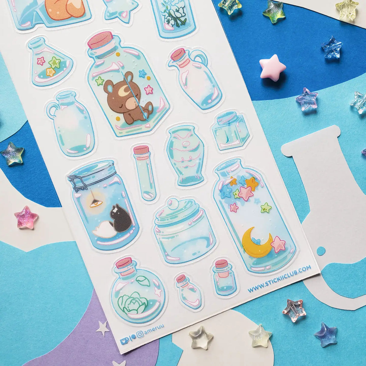 🌙🦊 Bottled up and brimming with magic, @ameruu transforms tiny jars into whole little worlds you can hold in your hands. Sleepy foxes and bears curl up for a nap, twinkling stars sparkle beside crescent moons, and delicate blooms and tiny treasures are tucked safely behind glass. From star-shaped vials to oversized bottles holding fragments of the night sky itself, this sheet is a pocket-sized universe, ready to sprinkle some stardust onto your favorite spreads.

Art by: @ameruu