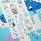 🌙🦊 Bottled up and brimming with magic, @ameruu transforms tiny jars into whole little worlds you can hold in your hands. Sleepy foxes and bears curl up for a nap, twinkling stars sparkle beside crescent moons, and delicate blooms and tiny treasures are tucked safely behind glass. From star-shaped vials to oversized bottles holding fragments of the night sky itself, this sheet is a pocket-sized universe, ready to sprinkle some stardust onto your favorite spreads.

Art by: @ameruu