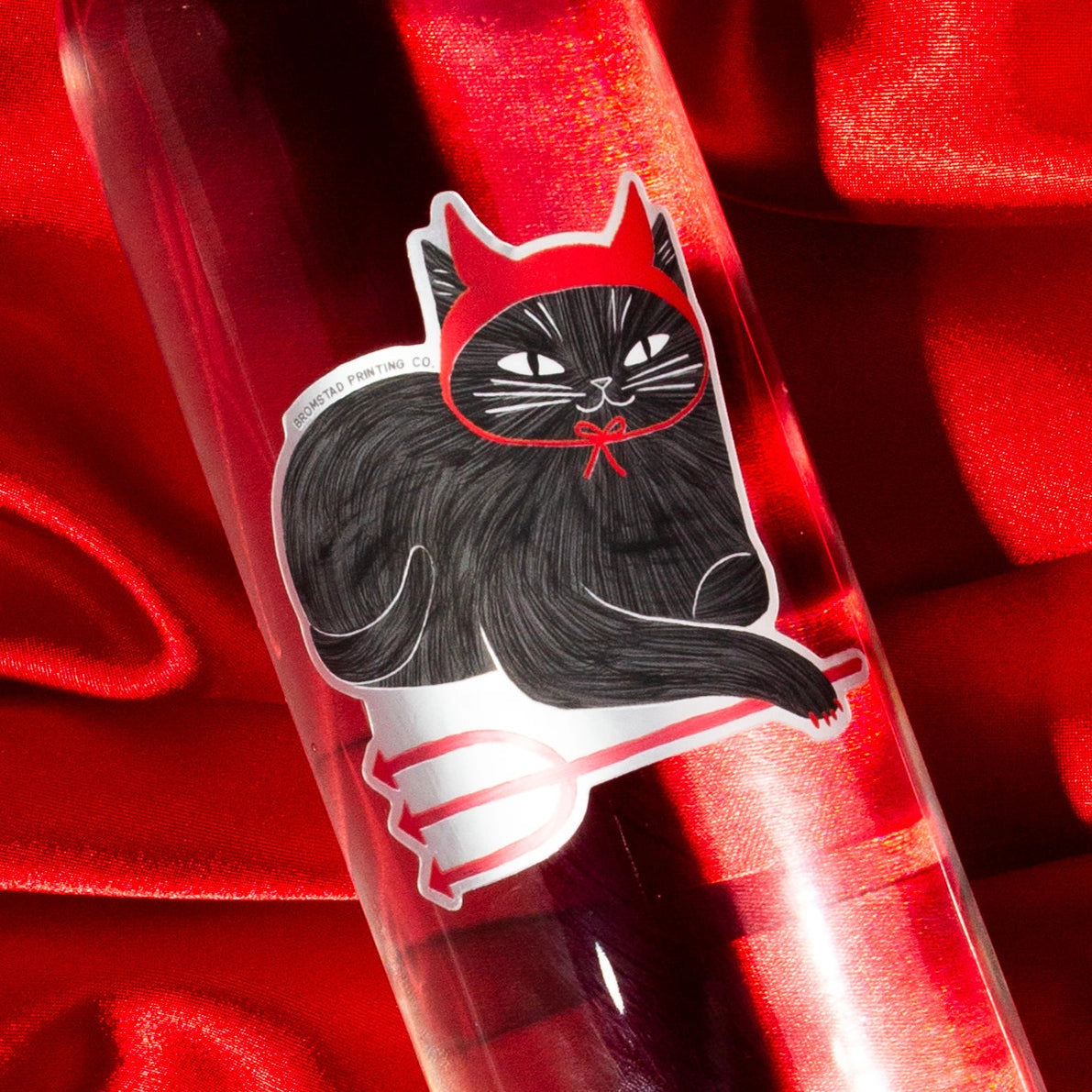 A mischievous cat decked out in devil horns and little pitchfork! This 3" cat sticker is made of a frosted mirror material with shiny red areas, making it purrfect for adorning water bottles, laptops, and more.