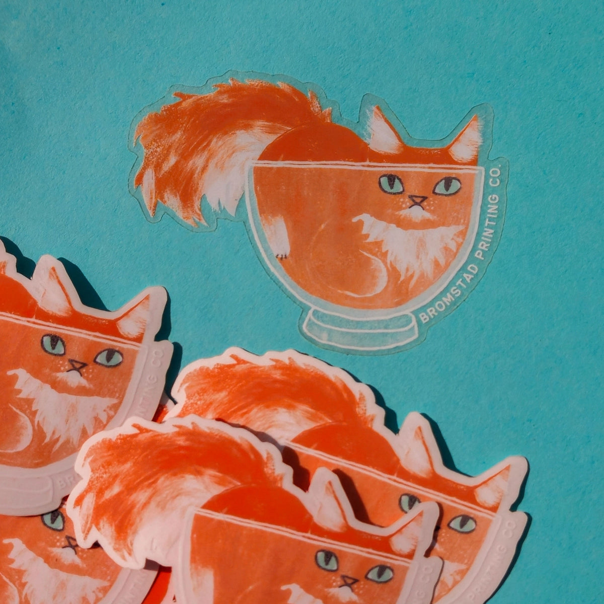 Cats are liquid, we know this. An orange boy has made himself comfy inside a clear glass bowl, fluffy tail and ears protruding. This 3" clear matte sticker is purrfect for adorning water bottles, laptops, and more. The white lines on the clear sticker pop on colorful backgrounds.