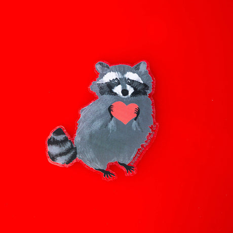Who can resist a cute little trash panda, and one clutching a little red heart no less! This raccoon has clearly stolen yours. This 3" clear sticker is transparent around the edges of the image and ideal for adorning water bottles, laptops, and more.
