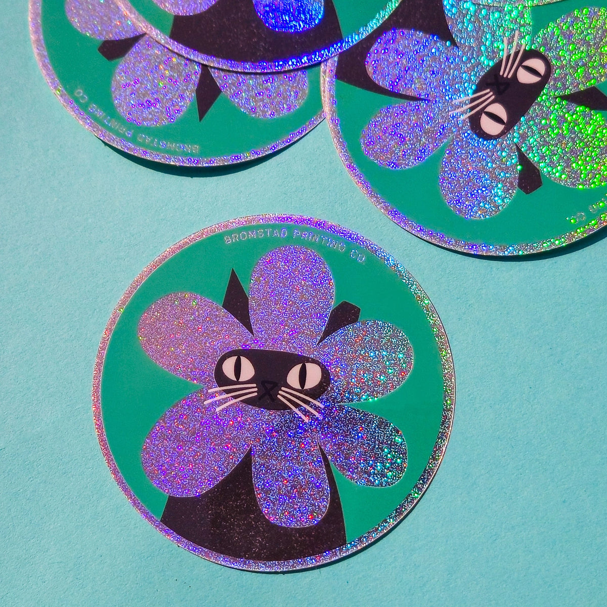 Product description
A black cat with a clipped ear wears a sparkly flower around their face. Truly, the rarest bloom. This 3" super sparkly glitter sticker is purrfect for adorning water bottles, laptops, and more. Watch how it catches the light!