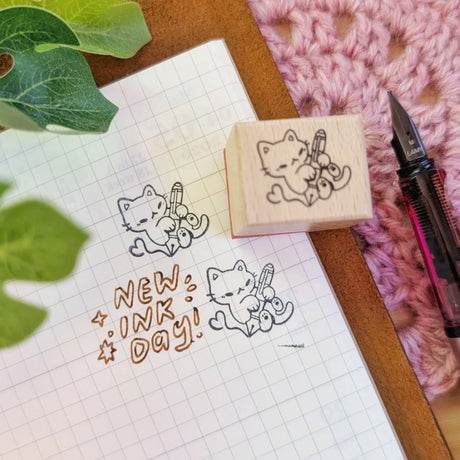 A small wood stamp of a kitty playing with a fountain pen for your planner and scrapbooking needs. Each stamp measures approximately 1 x 0.75 inch.