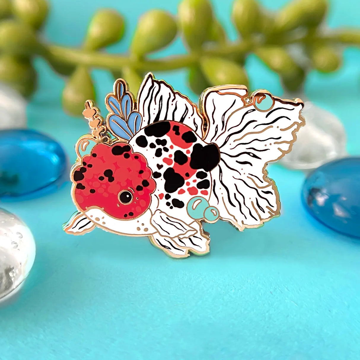 Celebrate your love for goldfish with this calico oranda pin!

✦ Hard enamel
✦ Shiny gold metal
✦ Screen-printed details
✦ 1.25 inches
✦ 2 Posts for extra security
✦ Rubber backings
✦ Back stamped for authenticity

Comes packaged on a backing card!&nbsp;