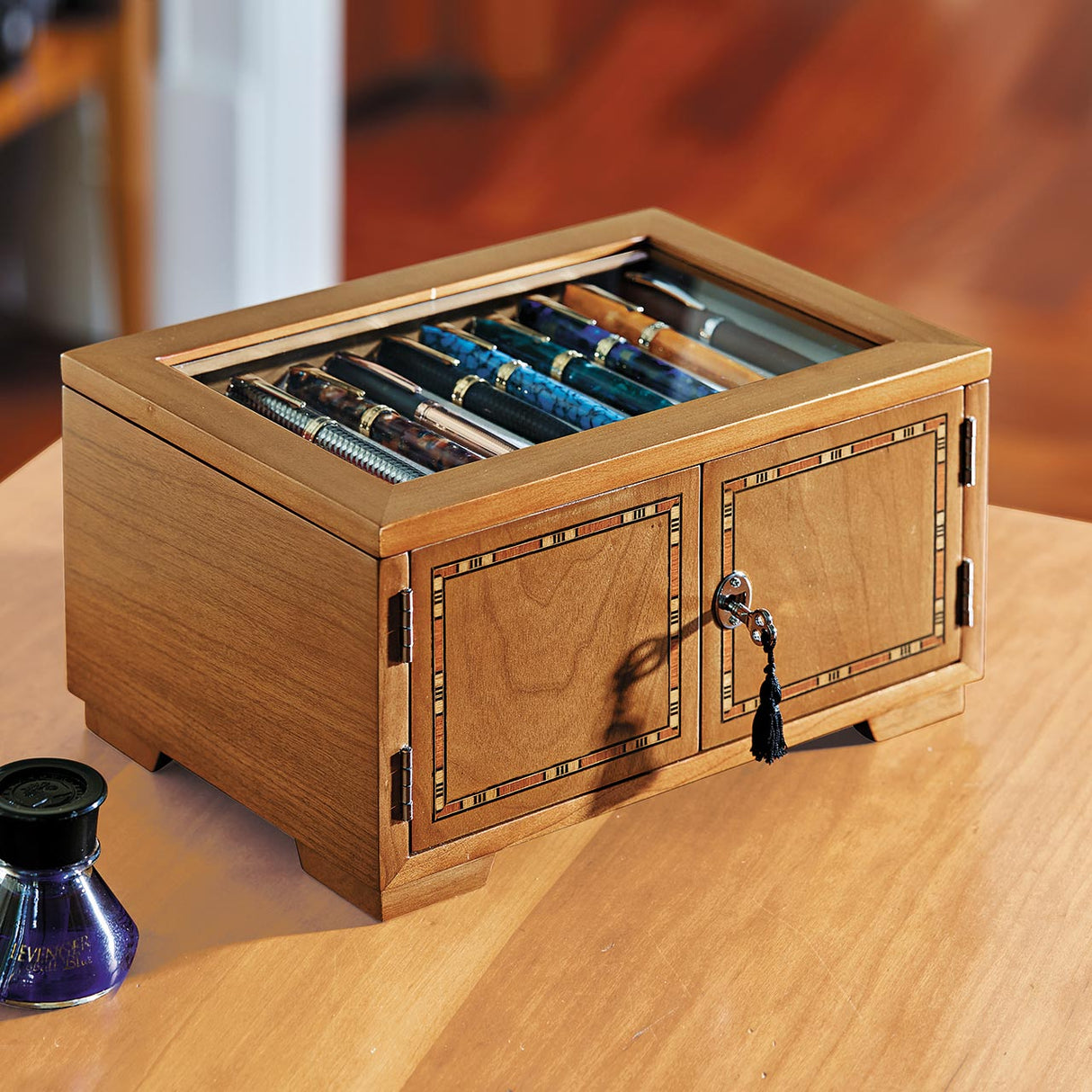 Our dramatic pen case for collectors, with new upgrades to accommodate larger styles. Part of the pleasure of being a pen lover is visual; a certain satisfaction ensues from being able to admire your favorites (and have others do the same). Our Lock and Key Pen Case offers more than an attractive space for displaying your prize pens—it also keeps your collection protected and free from dust. Unlock the wood inlay doors and lift the hinged protective glass lid to reveal the 4 drawers, each with 10 suede-line