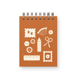 Buttons, Stamps, pencils and more! Playful and practical, the Craft Supplies Mini Jotter is perfect for jotting down project notes, lists, or creative ideas. Keep it handy for your next craft session!

Additional Details :

3”x4"
65 Unlined Interior Pages
Uncoated Vellum 70# Text Off-White Interior Paper
Bronze Wire-O Binding
Locally Made in Lawrence, Kansas