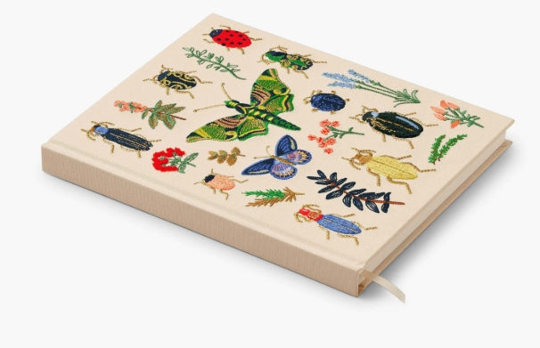 Our embroidered sketchbook is a large, hardcover journal with 108 unlined pages of thick paper perfect for sketching, drawing, and journaling. The cover is wrapped in cream book cloth and embroidered with the beetles and bugs of our Curio print with metallic gold accents. An attached grosgrain ribbon bookmark will save your place.