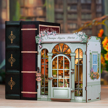 DIY Book Nook Kit: Champs-Elysees Florist
This elegant miniature captures the beauty of a boutique flower shop, adorned with delicate blooms, pastel accents, and a graceful arched doorway that invites you inside.

From the dainty floral arrangements to the hand-painted shop signs and warm, glowing interior, every detail evokes the feeling of strolling down the Champs-Élysées on a sunny afternoon. The soft LED lights cast a welcoming glow, highlighting rows of flowers ready to be wrapped for someone special.