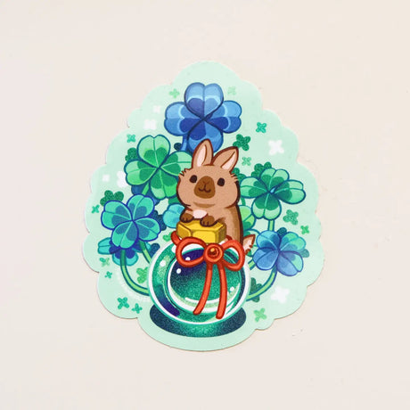 Sticker with a cartoon rabbit holding a clover and a bow on a light green background