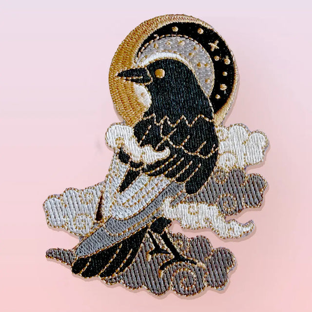 This fabulous patch features a black crow surrounded by grey glittery clouds, and a starry moon with grey backgrounds.

Beautifully woven with black, white, grey & gold threads, this fabulous patch with brighten up any coat, bag or hat!

Measurements: 70mm x 90mm