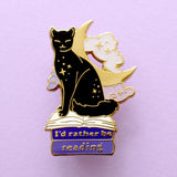 We’ve all sometimes wished we were at home with a hood book, rather than having to deal with the real world! This super cute pin features a black cat sitting on pink &amp; purple books with the slogan ‘I’d rather be reading’. Behind the cat is a large crescent moon and a pair of glittery pastel clouds.

Measurements: 45mm (1.77”)