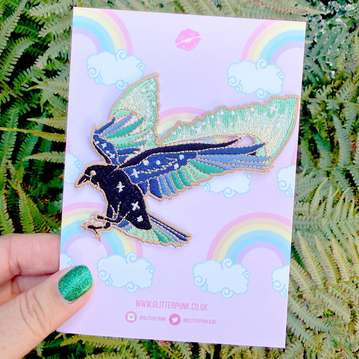 This amazing patch features a raven with its wings outstretched and the northern lights fanning out behind it.

Beautifully woven with black, green, blue & gold threads, this fabulous patch with brighten up any coat, bag or hat!

Measurements: 85 x 87mm