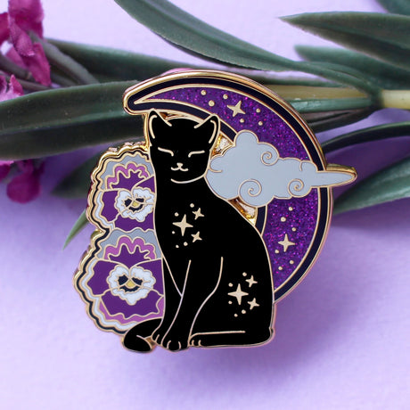 Celebrate your Pride with this fabulous Pansies Cat pin!

It features a black cat in front of a sparkly purple moon, next to some pansies in the black, grey, white & purple colours of the Ace Pride flag.

Each pin has a pair of heart shaped rubber pin backs, and is presented on a Pride themed Glitter Punk backing card. This pin is part of my Pride Cats collection, a 10-part set of enamel pins celebrating pride!

Measurements: 39mm (1.53”)