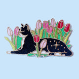Cats love nothing better than relaxing in a flower bed – and this cute cat is no exception! This awesome embroidered patch features a black and white tuxedo cat lying down in some pink tulips.

Beautifully woven with black, white, pink, green and gold threads, this fabulous patch with brighten up any coat, bag or hat!

Measurements: 100mm wide