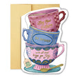 Bright, joyful, and full of heart. This colorful stack of teacups features magenta, teal, and blue hues with gold-foiled handwritten text reading “May your birthday be infused with all that brings you joy.” A tiny birthday cake appears on the teabag tag for an extra dose of delight.

Product Details:
- Dimensions: 5" x 7"
- Die-cut greeting card shaped like a stack of teacups
- Hand-illustrated with gold foil details
- Blank interior
- Offset and foil printed

Perfect for: tea lovers, Birthday celebrations,