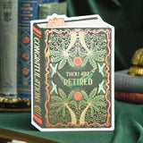 A witty book-shaped retirement card for those ready to begin their next chapter. This dark green vintage-style cover features golden palm trees and hammocks in a repeating pattern, with “Thou Art Retired” gleaming across the front in gold foil. A perfect mix of humor and elegance for celebrating well-earned rest.

Product Details:
- Dimensions: 5" x 7"
- Die-cut vintage book design
- Hand-illustrated with gold foil accents
- Blank inside
- Offset and foil printed
- Envelope included