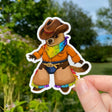 This sticker features my illustration of a groundhog cowhand showing off their rainbow bandana and rainbow-fringed chaps. The steely glint in their eye lets you know that they mean business about supporting queer folx!

This die-cut gloss vinyl sticker is durable, weatherproof, and perfect for water bottles, notebooks, laptops, bikes, and all sorts of other surfaces! Make sure to clean and dry the surface thoroughly before applying.
