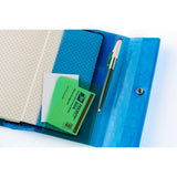Color-blocked in blue and green, the pocket in green adds a pop of color and is finished with an embossed shrink leather texture. The two colors and patterns overlap to create depth in the design.

The pen hook holds a pen by its clip. This cover does not include bookmarks.