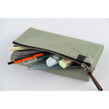 Its standout feature is the generously sized pocket, but its overall appearance remains clean and minimal. With its calming and gentle oakmoss color, the design is versatile and suits anyone. Though it folds into thirds and fastens with a magnetic closure, the cover is light in hand. The aim was effortless elegance, something that looks sharp without being flashy. The material is a soft nylon with a sophisticated sheen.