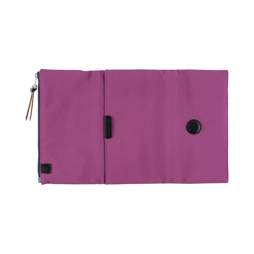 Its standout feature is the generously sized pocket, but its overall appearance remains clean and minimal. The aim was effortless elegance, something that looks sharp without being flashy. Adding a subtle pop is the reddish-purple color. It’s eye-catching yet refined, with a mature tone. Though it folds into thirds and fastens with a magnetic closure, the cover is light in hand. The material is a soft nylon with a sophisticated sheen.

