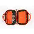 An open Hobonichi Mini Wallet in carrot orange color with black trim, displaying the interior which includes a small graph notebook and several pockets for cards and coins, alongside a detached carabiner.