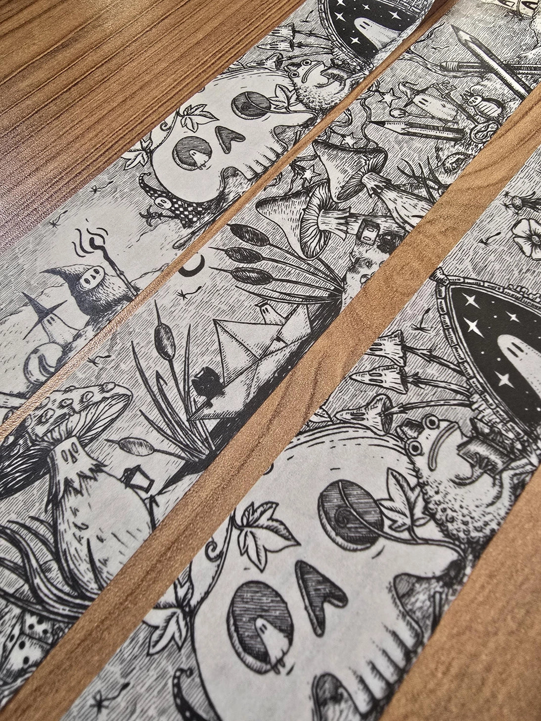 A unique and infinitely repeating fantasy landscape of melancholy oddities and curious characters, from original hand-drawn ink artwork by Jon Turner, recreated with incredible detail at miniature size in this washi tape that invites you to find new tiny details with every viewing.

This is a special extra-wide washi tape, 30mm high which really brings out all the tiny details. perfect for creating a decorative border when journalling, or for packing parcels with surreal style. 10m long.