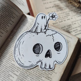 A little ghostie with a flower, perched atop a spooky skull, on a die-cut vinyl sticker. From original ink artwork by Jon Turner.