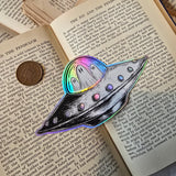 A spooky little UFO on a lovely die-cut holographic vinyl sticker from original pen and ink artwork by Jon Turner.
