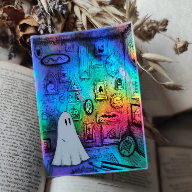 A little ghostie I'm a shiny gallery of curiosities, from my original artwork.

Die-cut vinyl holographic sticker, suitable for interior or exterior use; perfect for a phone, laptop, car, planner, or wherever you want to put a shiny robot. Measures approximately 7.5cm (3 inches) at its widest point. Difficult to photograph, but it shimmers beautifully under the light with an exciting oilslick rainbow effect.