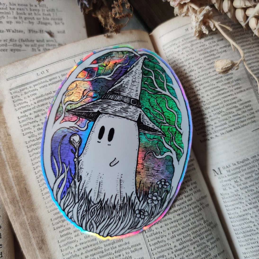 A magical ghostie on a shiny cosmic sticker, from my original artwork.

Die-cut vinyl holographic sticker, suitable for interior or exterior use; perfect for a phone, laptop, car, planner, or wherever you want to put a shiny robot. Measures approximately 7.5cm (3 inches) at its widest point. Difficult to photograph, but it shimmers beautifully under the light with an exciting oilslick rainbow effect.