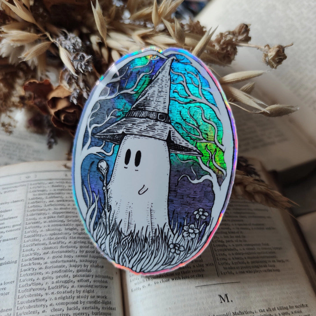 A magical ghostie on a shiny cosmic sticker, from my original artwork.

Die-cut vinyl holographic sticker, suitable for interior or exterior use; perfect for a phone, laptop, car, planner, or wherever you want to put a shiny robot. Measures approximately 7.5cm (3 inches) at its widest point. Difficult to photograph, but it shimmers beautifully under the light with an exciting oilslick rainbow effect.