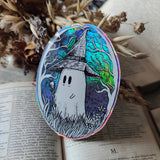 A magical ghostie on a shiny cosmic sticker, from my original artwork.

Die-cut vinyl holographic sticker, suitable for interior or exterior use; perfect for a phone, laptop, car, planner, or wherever you want to put a shiny robot. Measures approximately 7.5cm (3 inches) at its widest point. Difficult to photograph, but it shimmers beautifully under the light with an exciting oilslick rainbow effect.