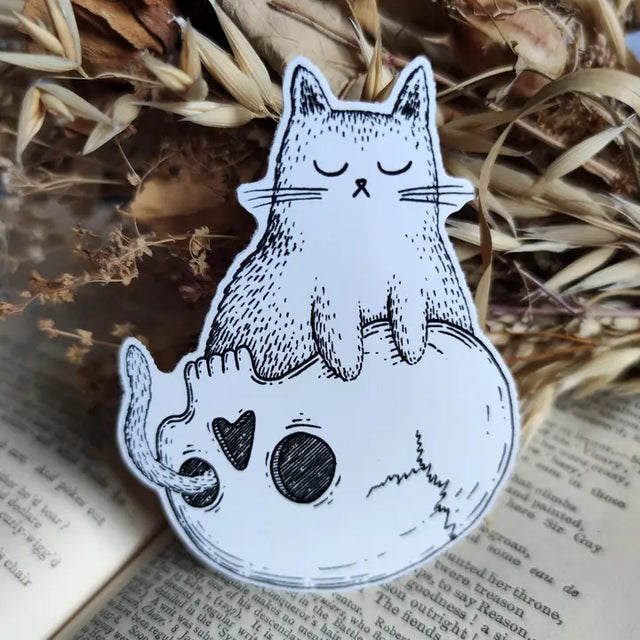 Sticker featuring a spooky little cat sitting contentedly on a skull, from my original pen and ink artwork.

Die-cut vinyl sticker, suitable for interior or exterior use. Measures approximately 7.5cm (3 inches) high, and 5cm (2 inches) wide.&nbsp;