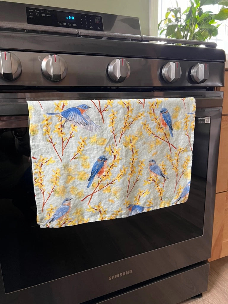 Introducing this bright spring colored pattern of blue birds and yellow forsythia that will add a touch of elegance and serenity to your home. Bringing a sweet whisper of the outdoors into your kitchen.

Crafted from 100% premium linen, this towel measures 17.5 x 26 inches, blending beauty with utility. Each comes with a belly band, perfect for gifting and a corner hang loop for hanging.

Designed by Kasey. Imported.

Artwork copyright Kasey Melissa Art 2025.