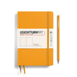 A hardcover Leuchtturm1917 Rising Sun notebook in orange color with a matching orange pencil, both featuring the brand's logo.